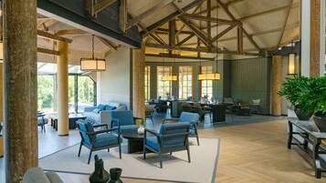 A spacious indoor area with wooden beams, a dining area, and seating arrangements.