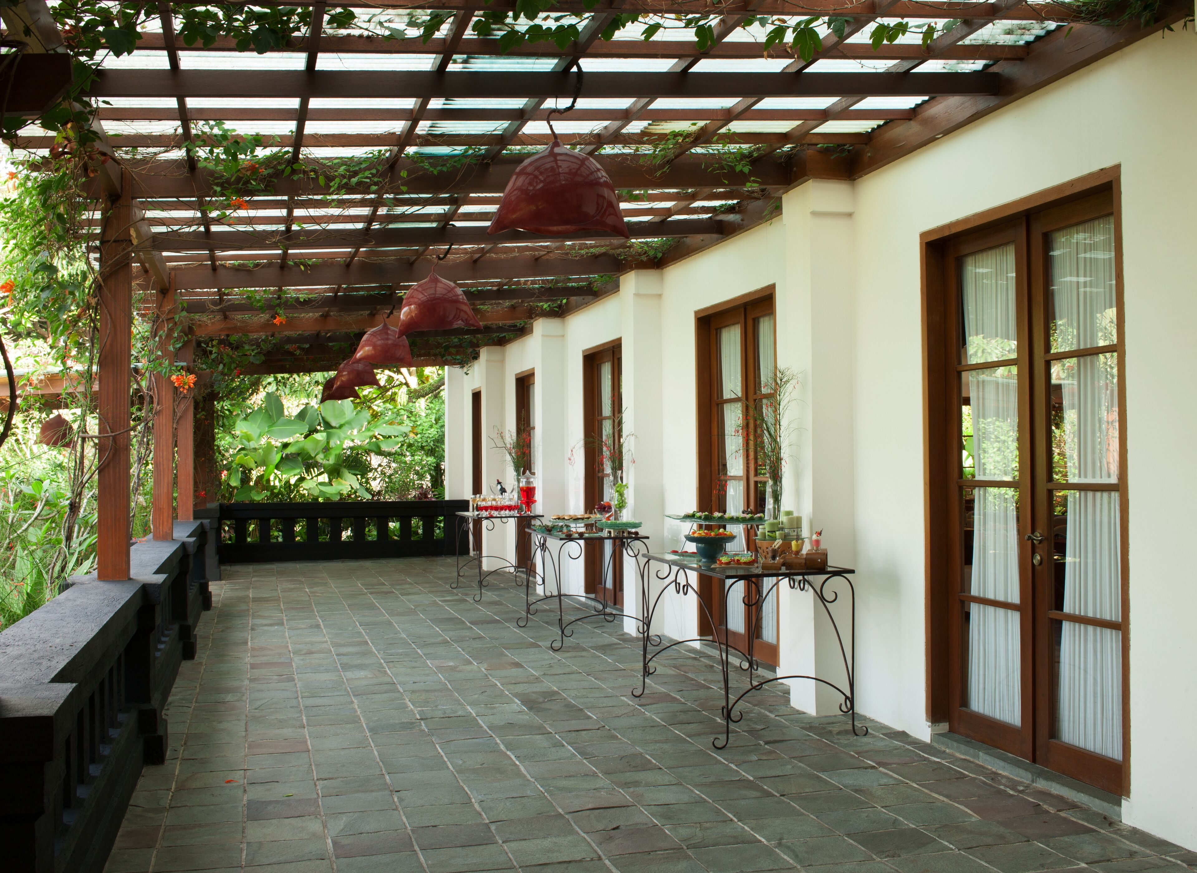 A covered outdoor area with a pergola, tables with potted plants, and benches.