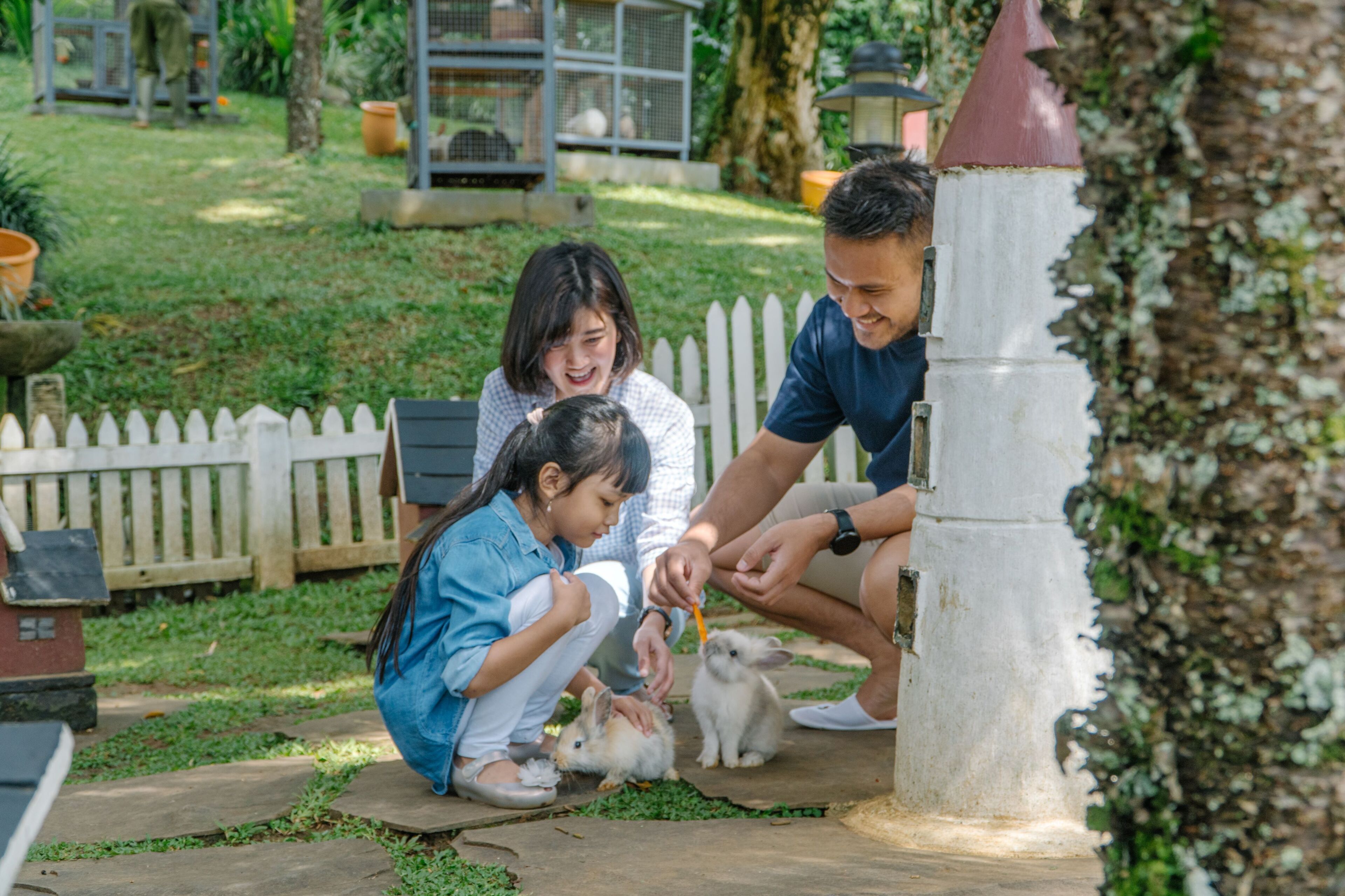 Una familia interactuando con conejos en un jardín.