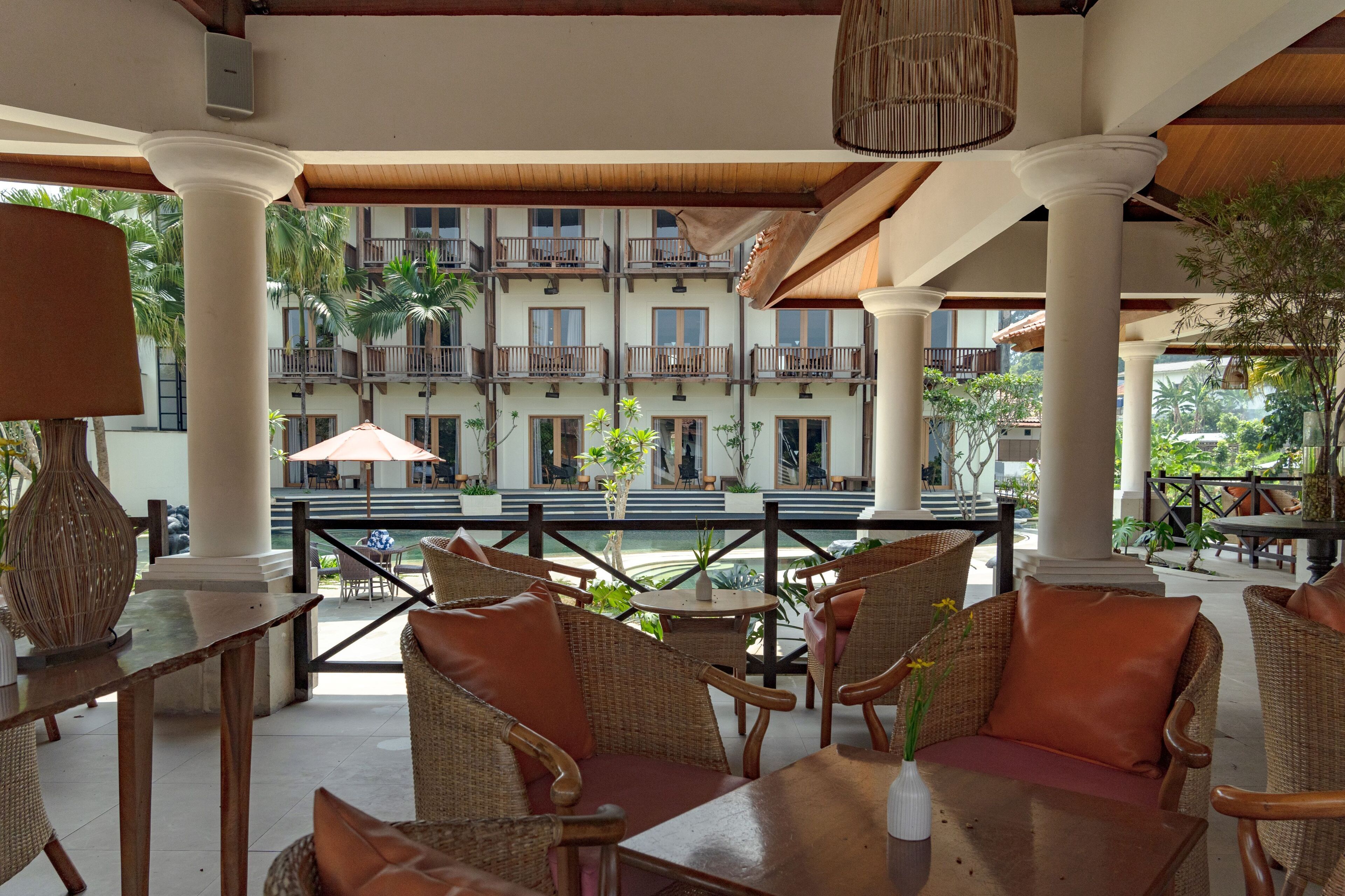 An outdoor seating area with wicker furniture and a view of a multi-story building with balconies.