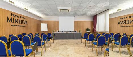 A conference room with blue chairs, a long table, and a projector screen.