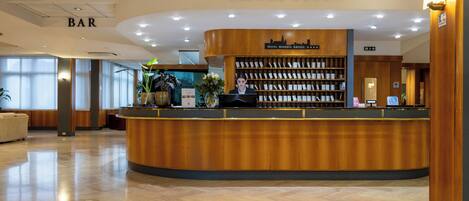 A reception area with a wooden counter, a reception desk, and a bar sign.