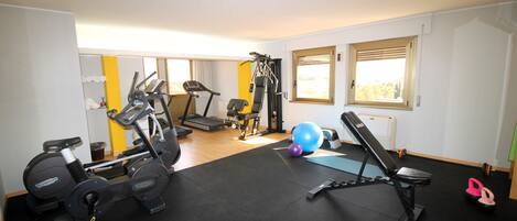 Ett gym med konditionsmaskiner, utrustning för styrketräning och träningsbollar.