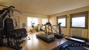 Un gimnasio con máquinas de cardio, equipo de levantamiento de pesas y una cinta de correr.