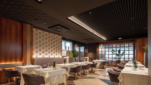 A restaurant with multiple tables, chairs, and a patterned wall. - Hotel Minerva (Arezzo)