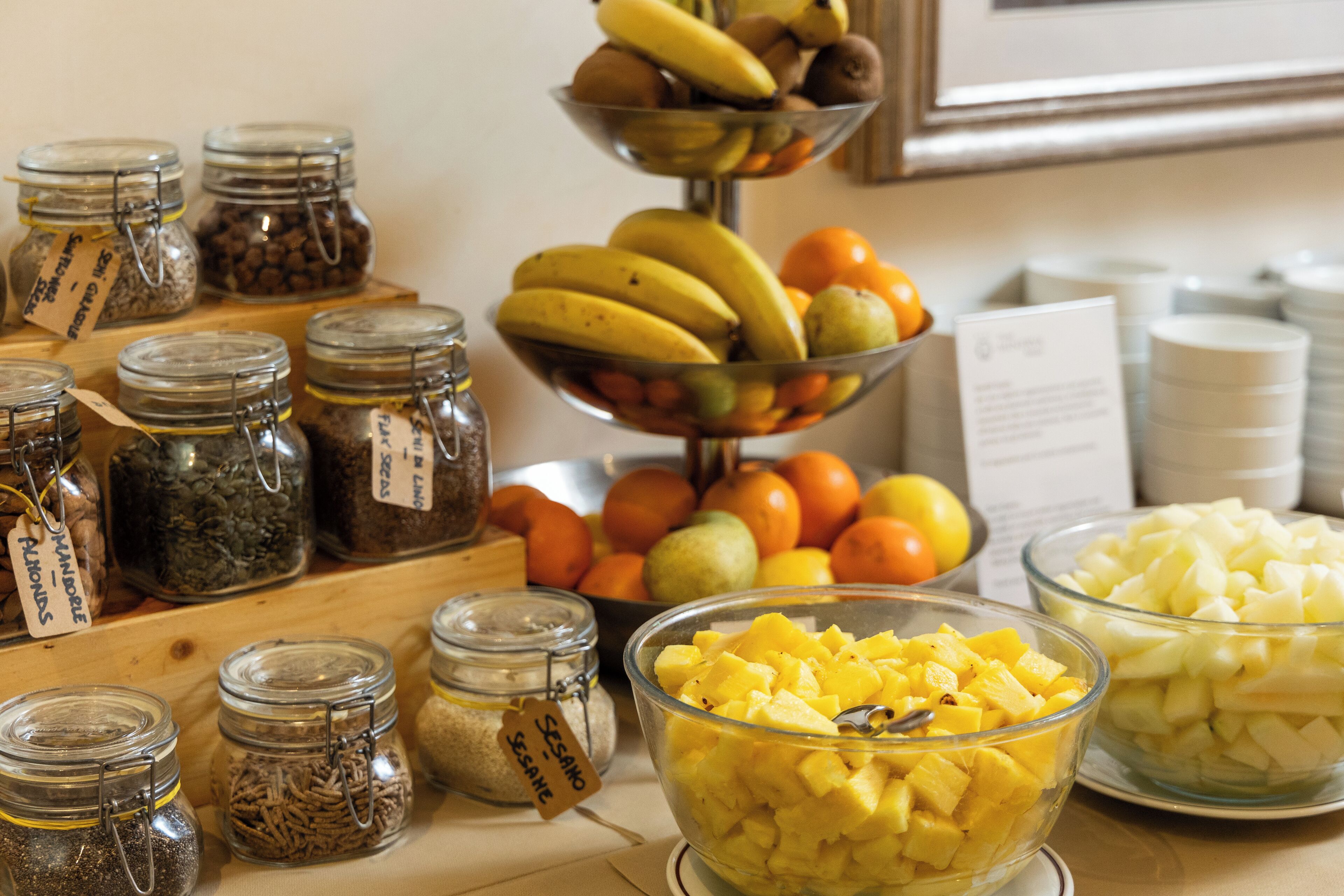 A variety of food items including jars of spices, a bowl of diced pineapple, and a fruit display with bananas and oranges.