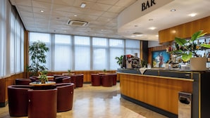 A bar area with a wooden counter, seating, and large windows. - Hotel Minerva (Arezzo)