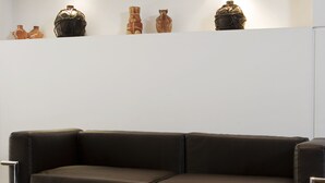 A modern living room with a brown leather sofa, a black coffee table with a bowl of food, and a white wall with decorative items. - Ayres Apartments Recoleta - Uriburu (Buenos Aires)