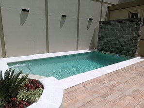 Una piscina rettangolare con bordo bianco, circondata da un solarium piastrellato.