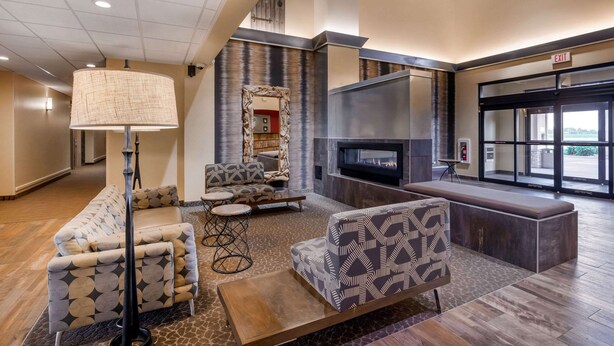 A lobby with a fireplace, seating area, and an exit sign.