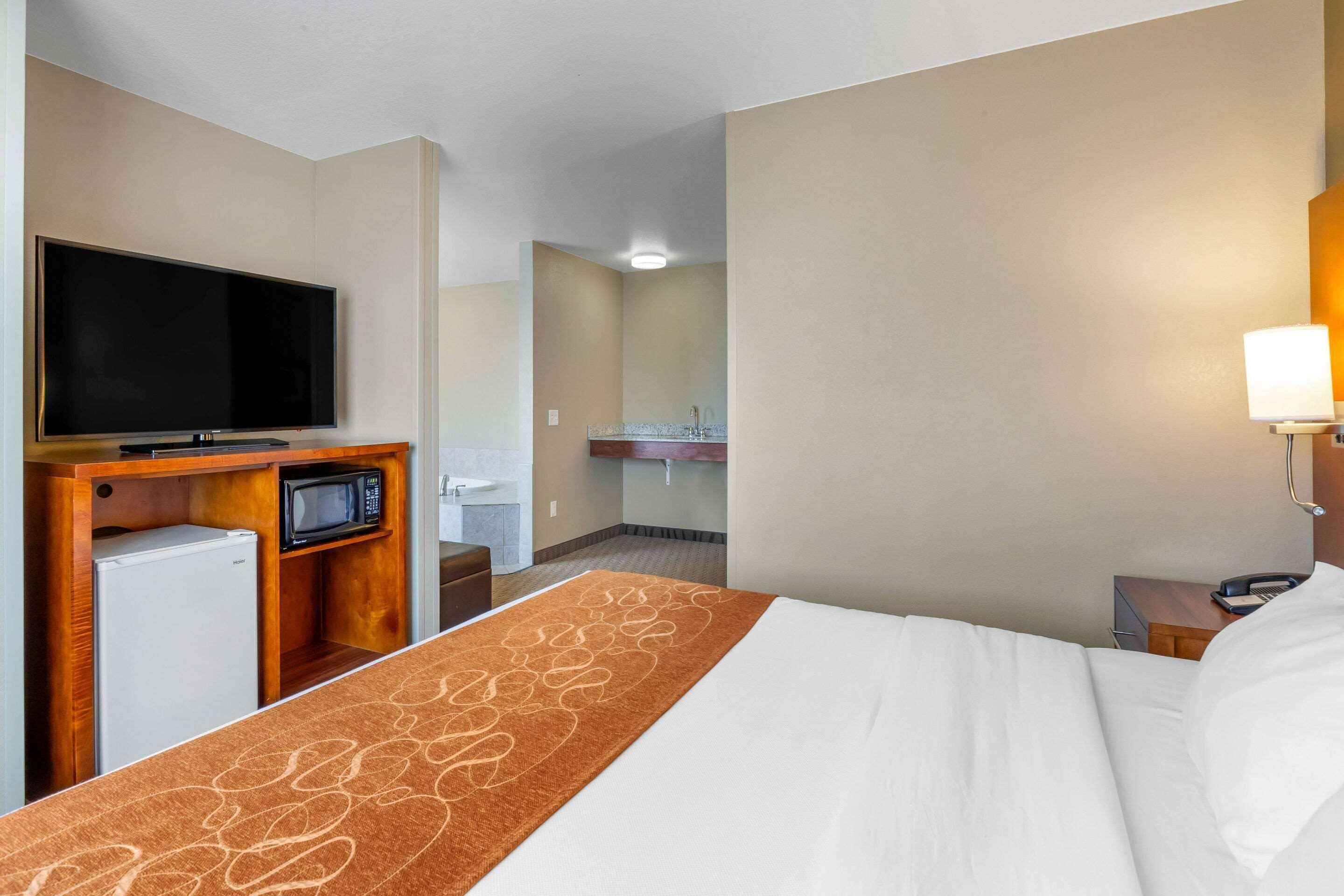 A hotel room with a bed, a TV, a microwave, and a small refrigerator.