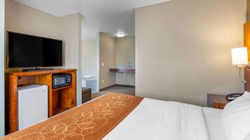 A hotel room with a bed, a TV, a microwave, and a small refrigerator.