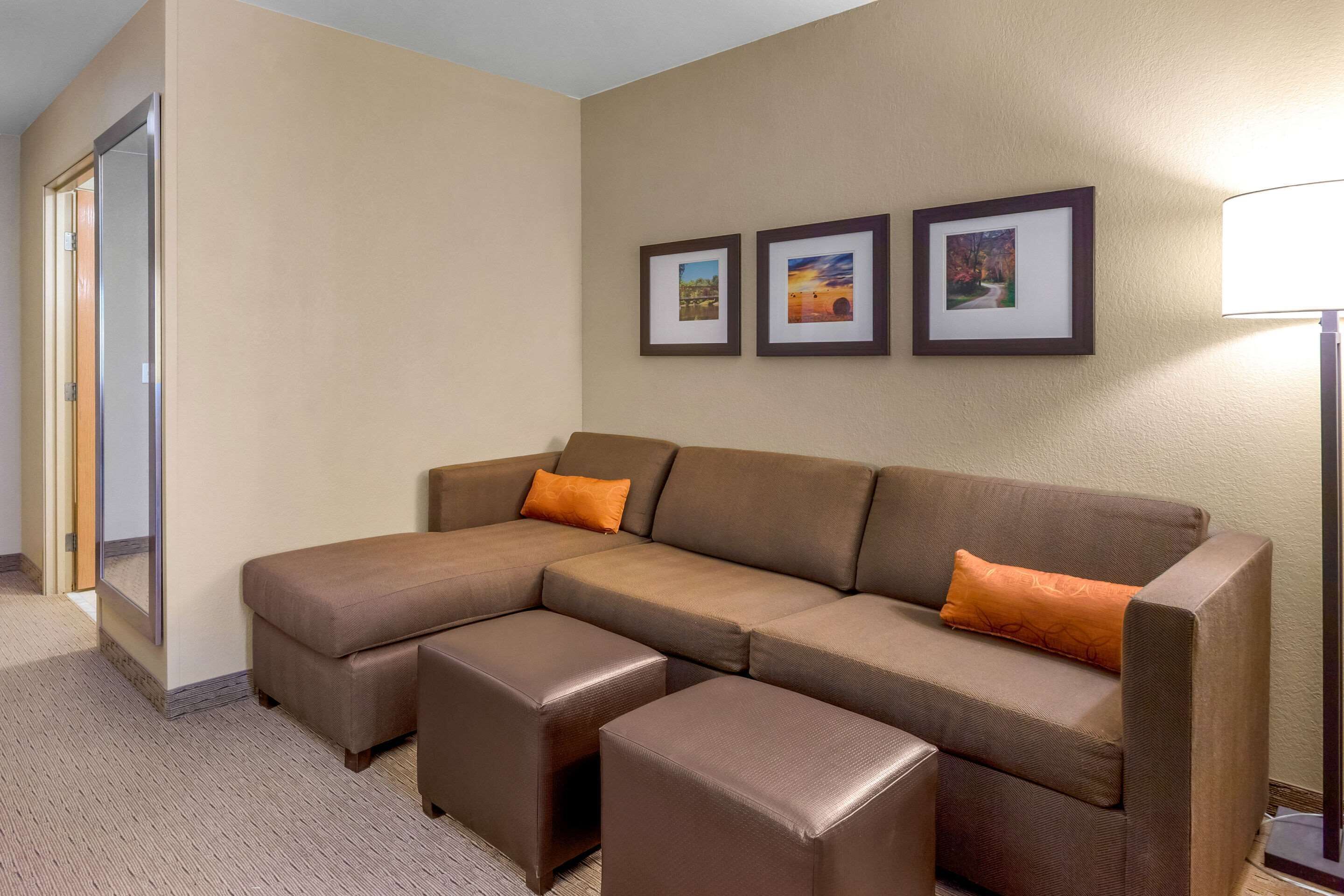 Un canapé modulable avec deux poufs, une porte et des tableaux encadrés accrochés au mur.