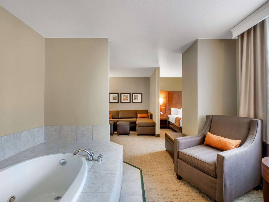 A hotel room with a large bathtub, a sofa, a chair, and a small table.