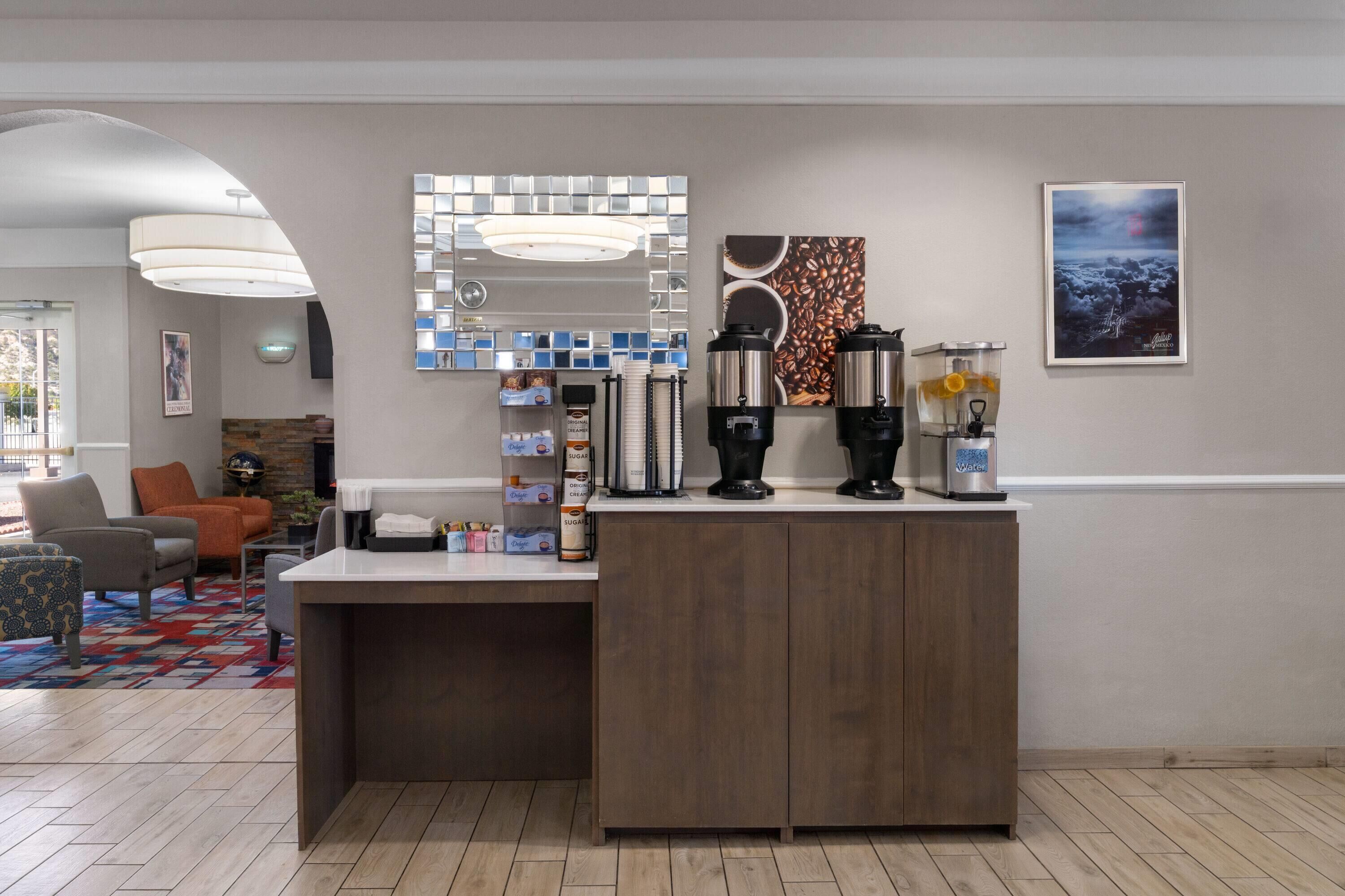 A modern reception area with a coffee station, seating area, and artwork on the walls.