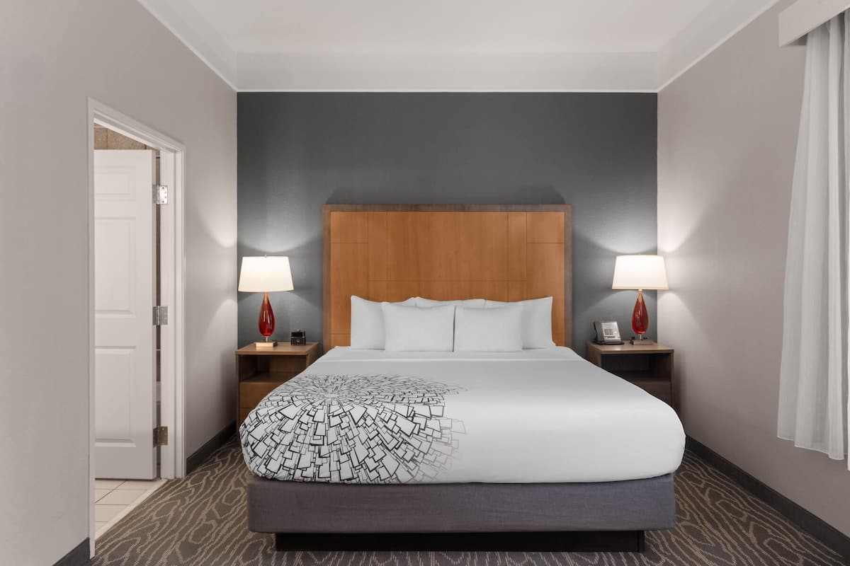 A hotel room with a large bed, two bedside tables, and a wooden headboard.