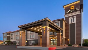 A hotel with a covered entrance, a prominent sign, and a well-lit facade. - La Quinta Inn & Suites by Wyndham Gallup (Gallup)