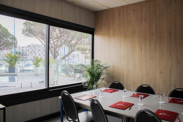 A conference room with a large window, a white table, and red placemats.