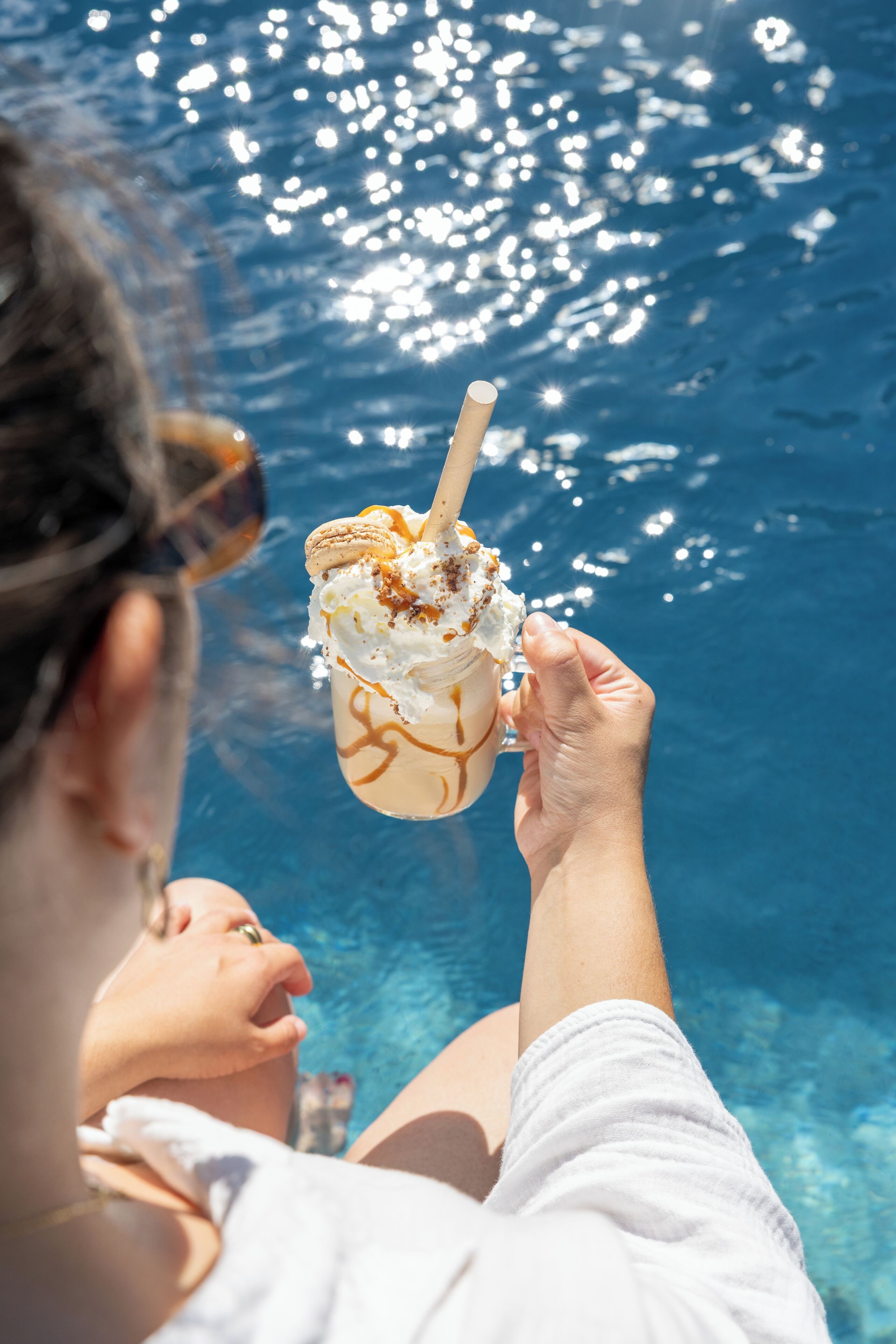 A person holding a dessert near a pool.