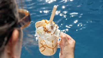 Una persona sosteniendo un postre cerca de una piscina.