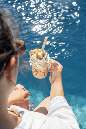 Eine Person hält ein Dessert in der Nähe eines Pools.