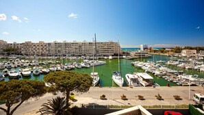 A marina with numerous boats docked, surrounded by buildings and greenery.