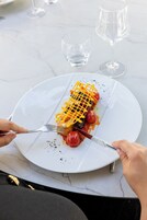A dining table with a white plate containing a meal, a fork, and a knife.
