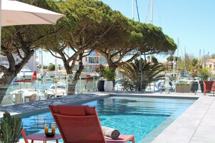 Una piscina al aire libre, sombrillas, sillones reclinables de piscina