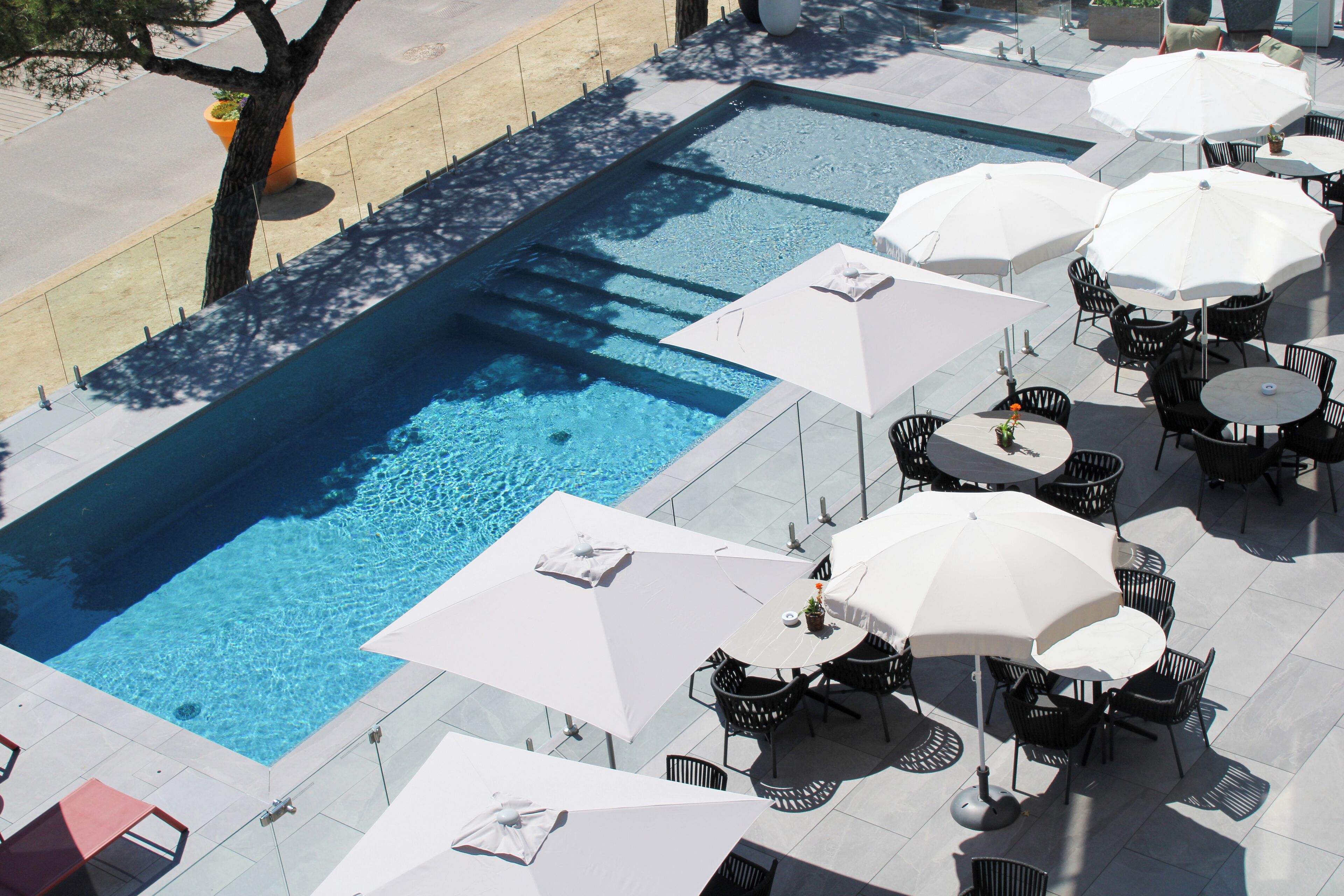 A swimming pool with surrounding outdoor seating and umbrellas.