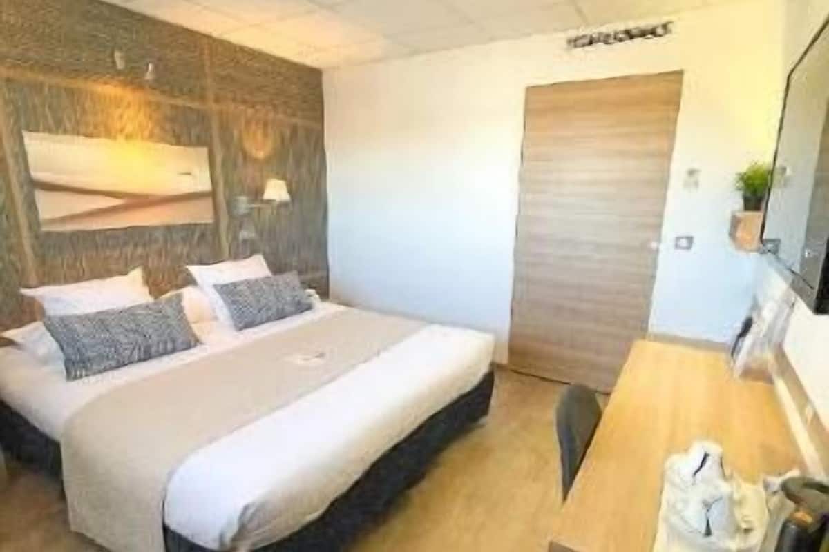 Ein modernes Hotelzimmer mit Bett, Schreibtisch und Spiegel.