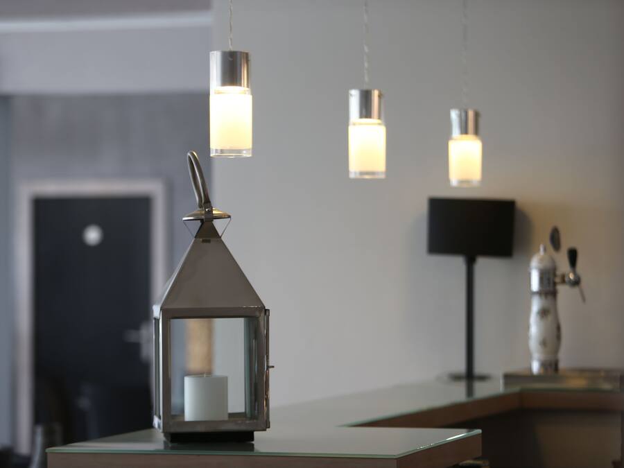 Un interior moderno con una mesa de recepción, un farol decorativo y lámparas colgantes.