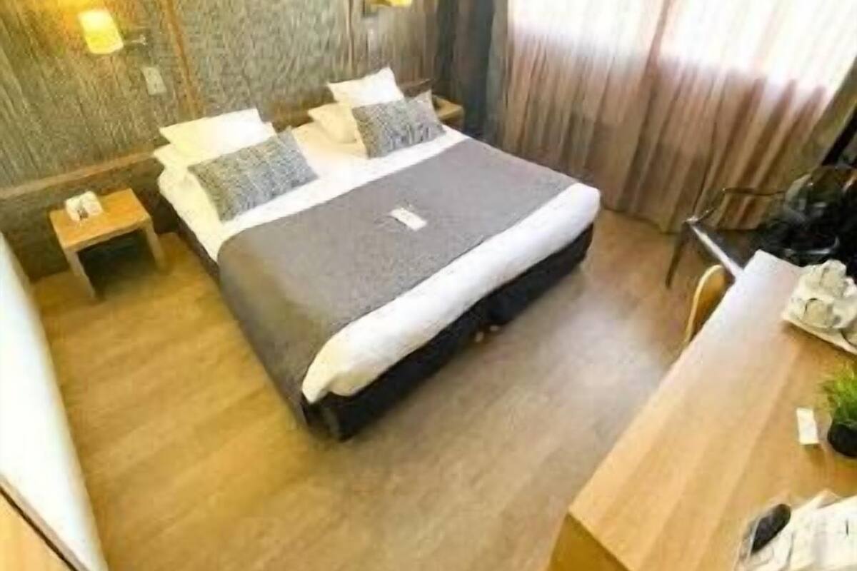 Una habitación de hotel con cama, mesitas de noche, un escritorio y una silla.