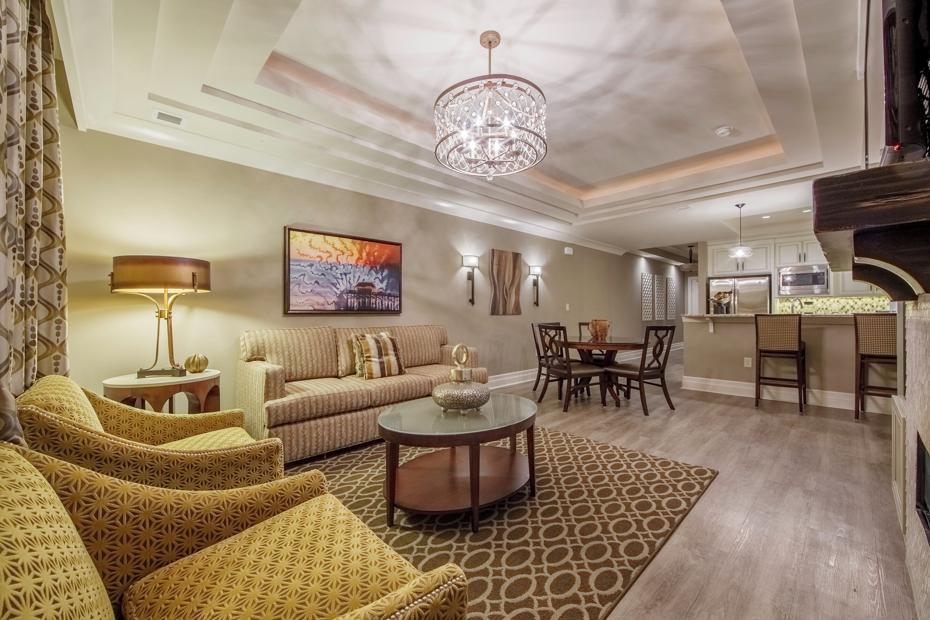 A modern living room with a sofa, patterned chairs, a coffee table, and a chandelier.
