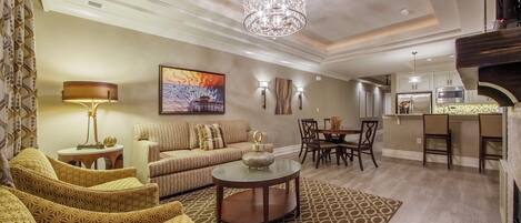 A modern living room with a sofa, patterned chairs, a coffee table, and a chandelier.