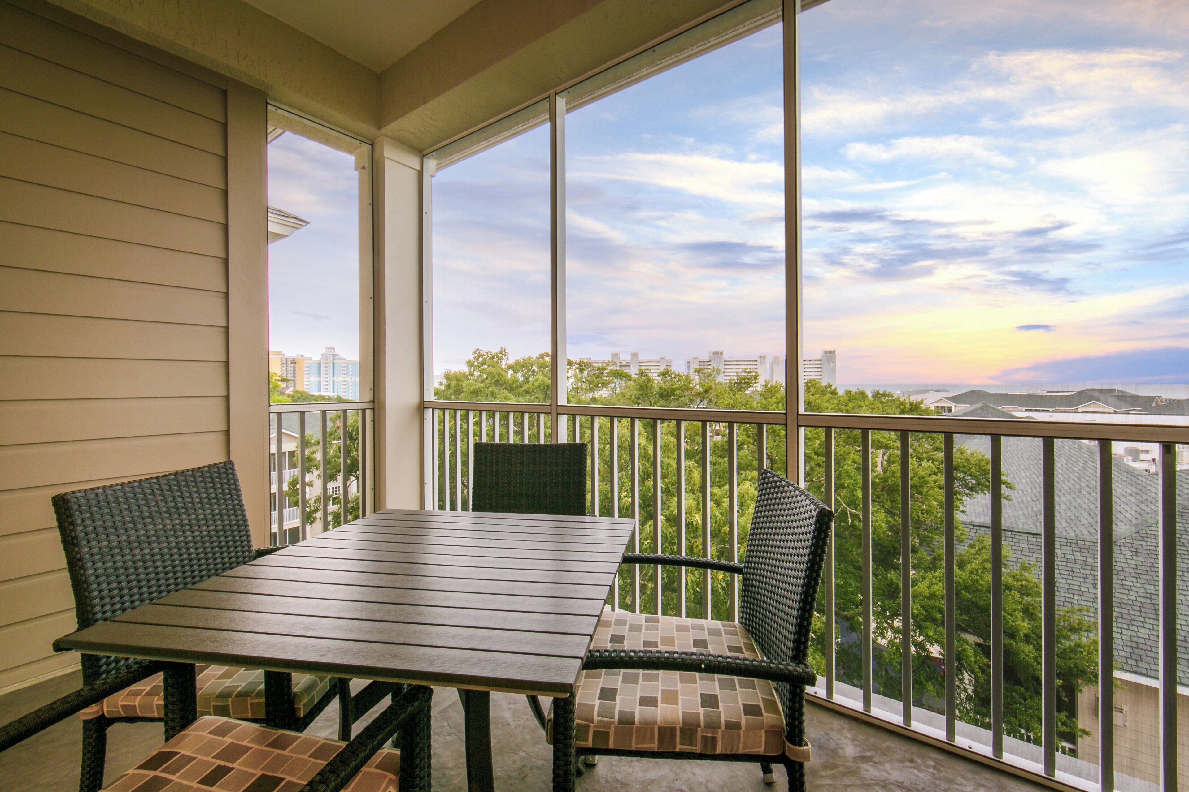 A balcony with a table and chairs, overlooking a cityscape and a body of water.