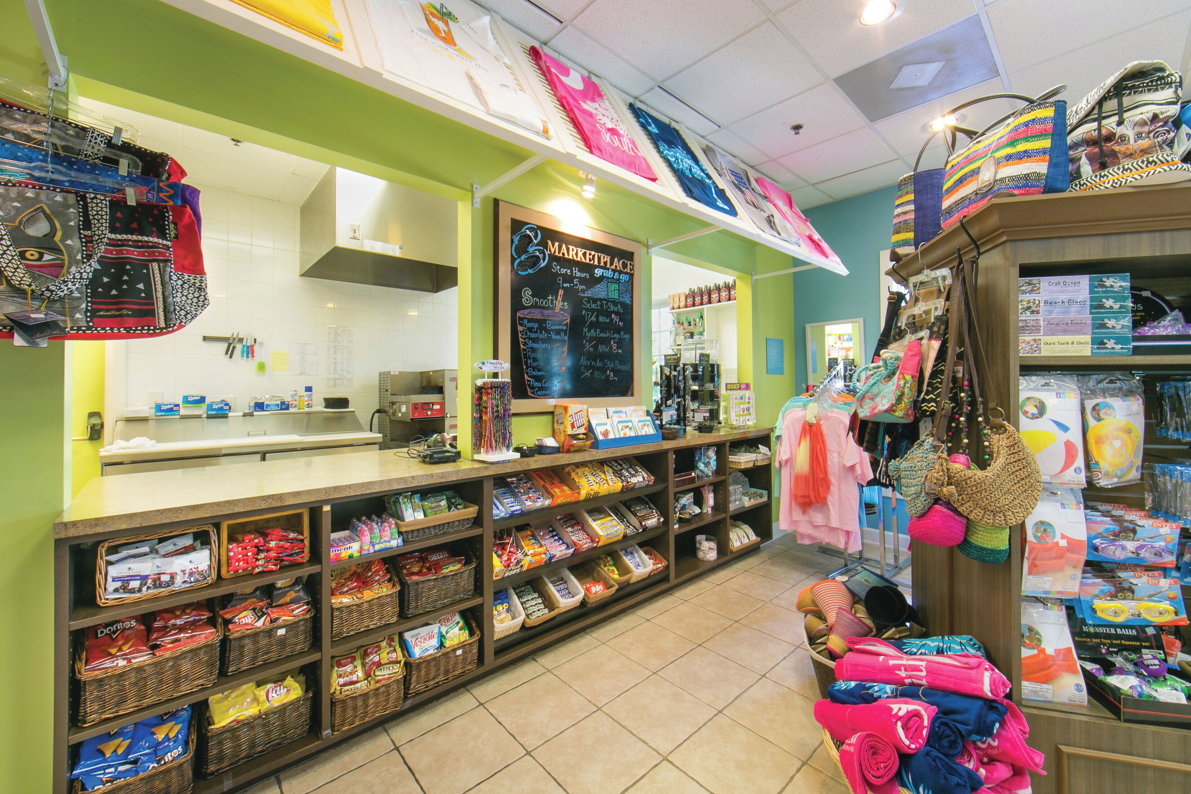 Un magasin bien éclairé, avec des étagères remplies d’en-cas, un comptoir de caisse, ainsi qu’une variété de sacs et d’accessoires aux couleurs vives.