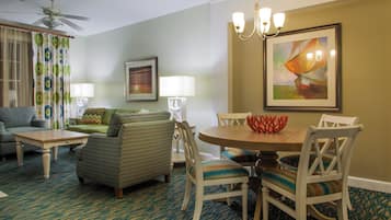 Una sala de estar con sofá, sillas, una mesa de comedor y una araña.
