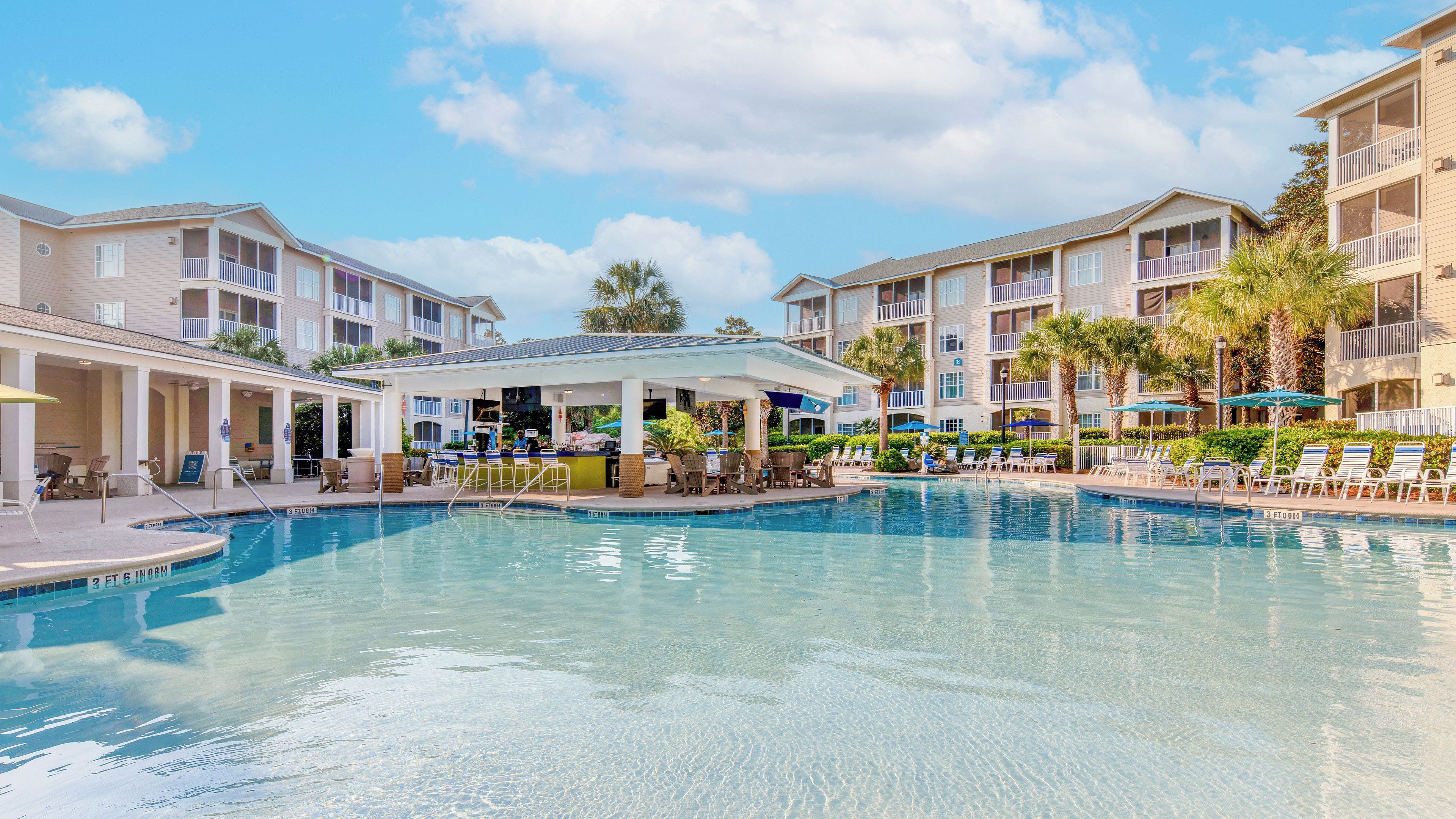 A resort with a swimming pool, lounge chairs, and a bar area.