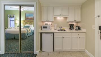 A compact hotel room with a kitchenette, a bed with a view, and a small refrigerator.