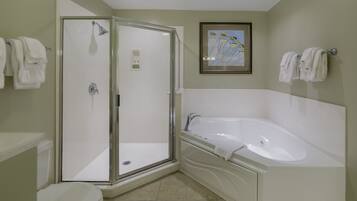 A bathroom with a glass-enclosed shower, a white bathtub, and a toilet.