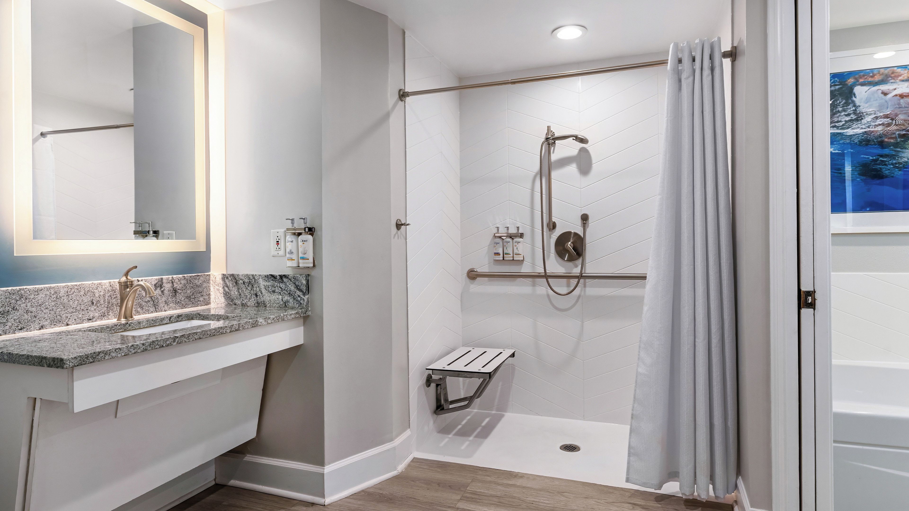 Un baño moderno con ducha, tocador y un espejo grande.