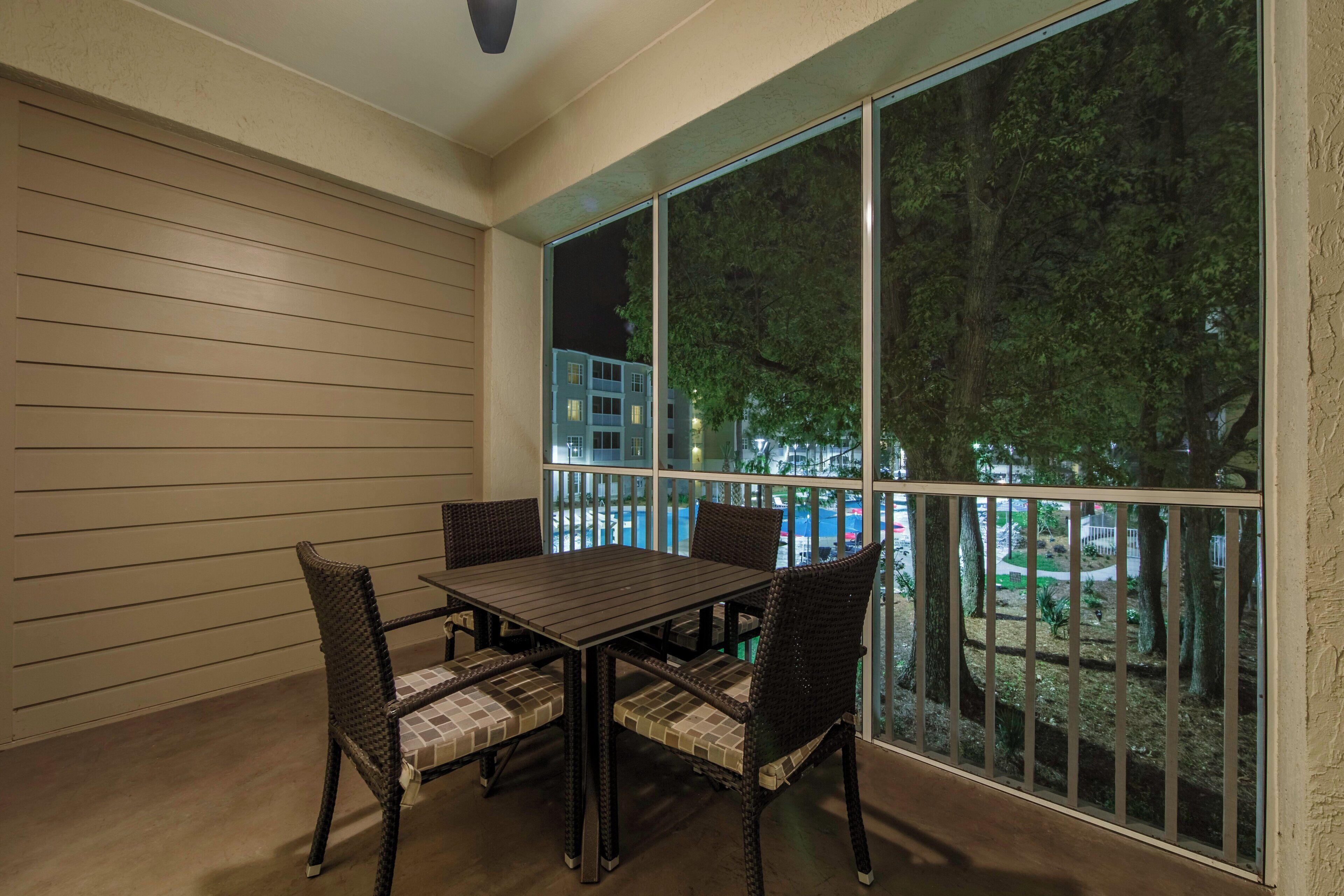 A balcony with a table and chairs, a view of a building, and a railing.