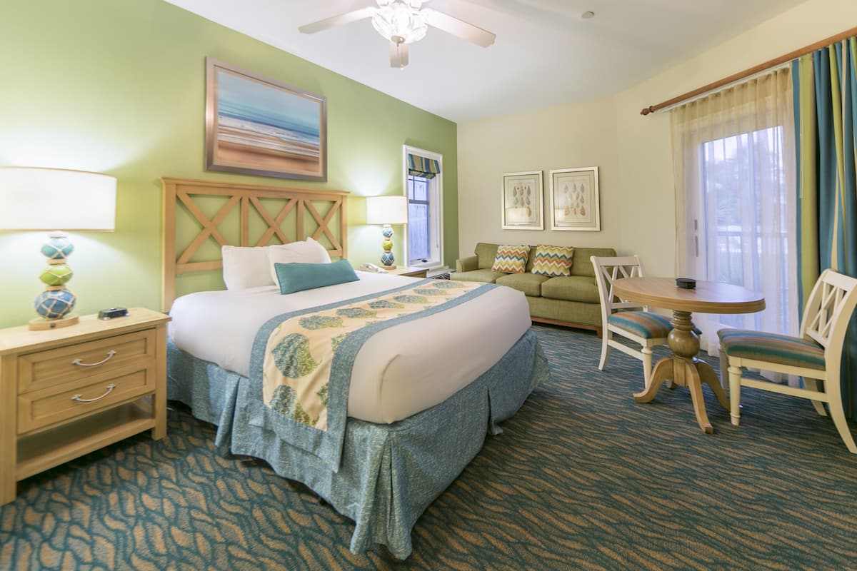 A hotel room with a bed, a desk, a chair, and a sofa.