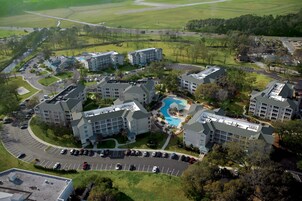 Vista aérea de un complejo hotelero con varias edificaciones, piscina y estacionamiento.