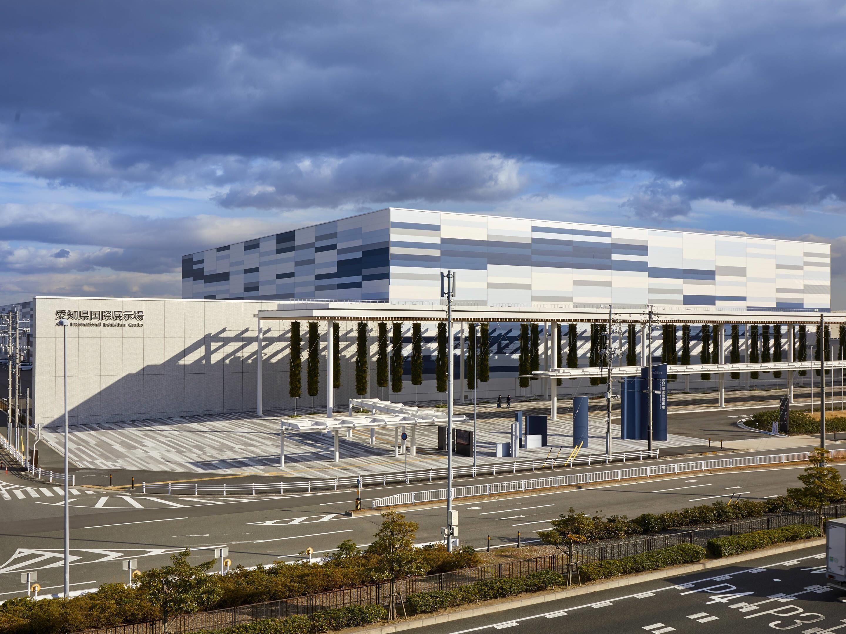 Un edifici modern amb façana geomètrica, una zona exterior coberta amb seients i un cel serè.