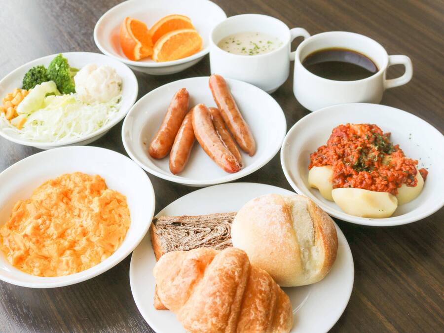 A table with various dishes including sausages, dumplings, and a bowl of orange-colored food.