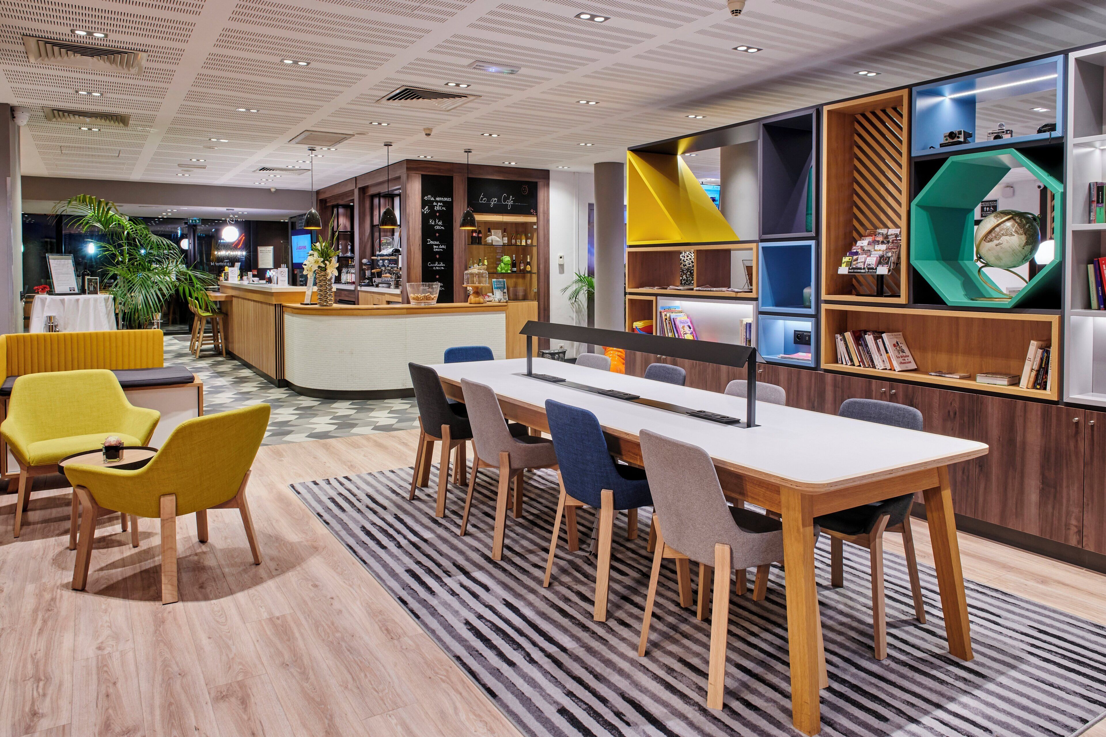 Un hall d’hôtel moderne comprenant un comptoir d’accueil, un espace salon et un bar.