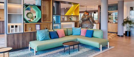 A modern lounge area with a green sectional sofa, a small coffee table, and a patterned rug.