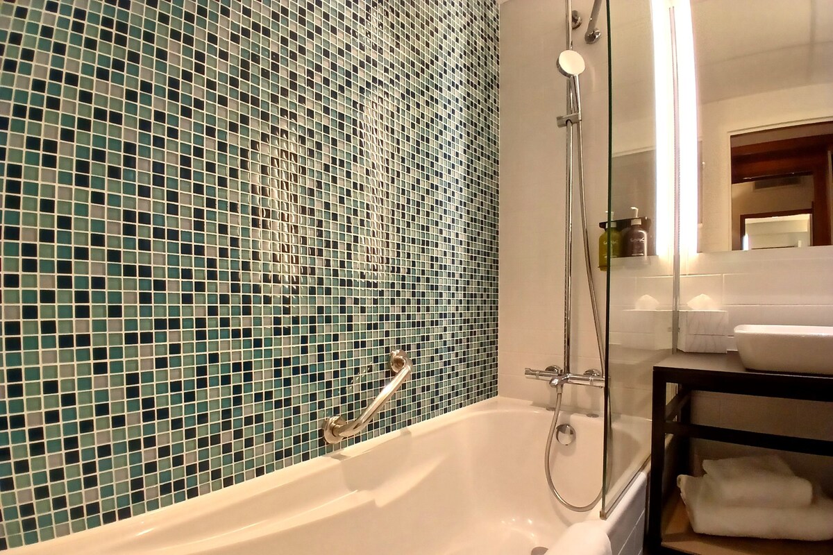 A bathroom with a bathtub, a shower, and a sink.