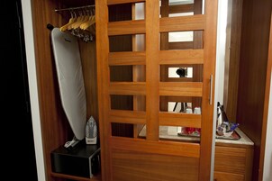 Un armario de madera con espejo, una barra para colgar ropa y un estante con diversos objetos.